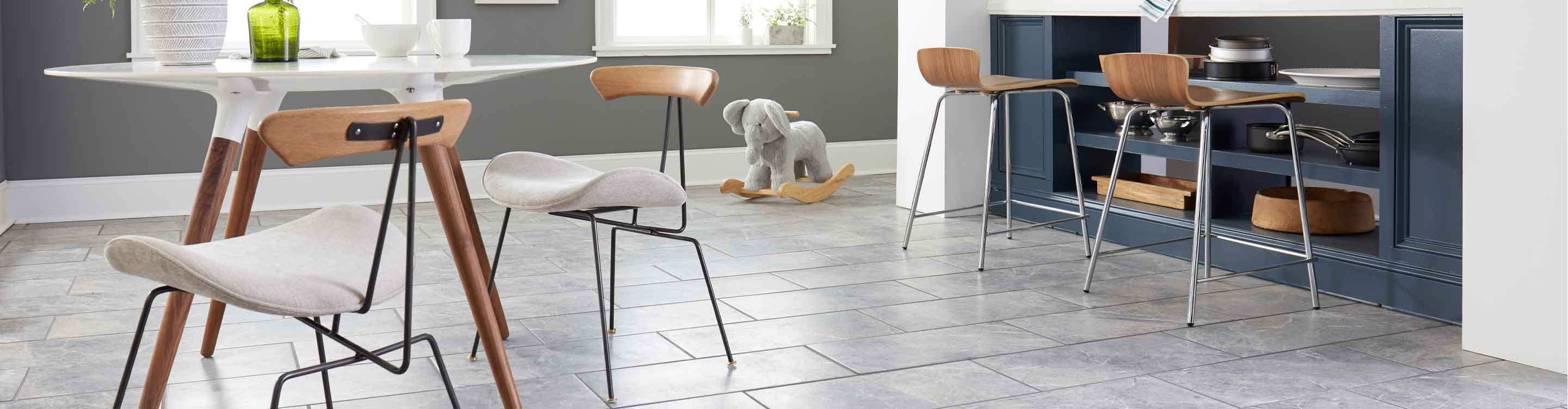 modern kitchen with gray marble look tile flooring and blue kitchen island, wood barstools
